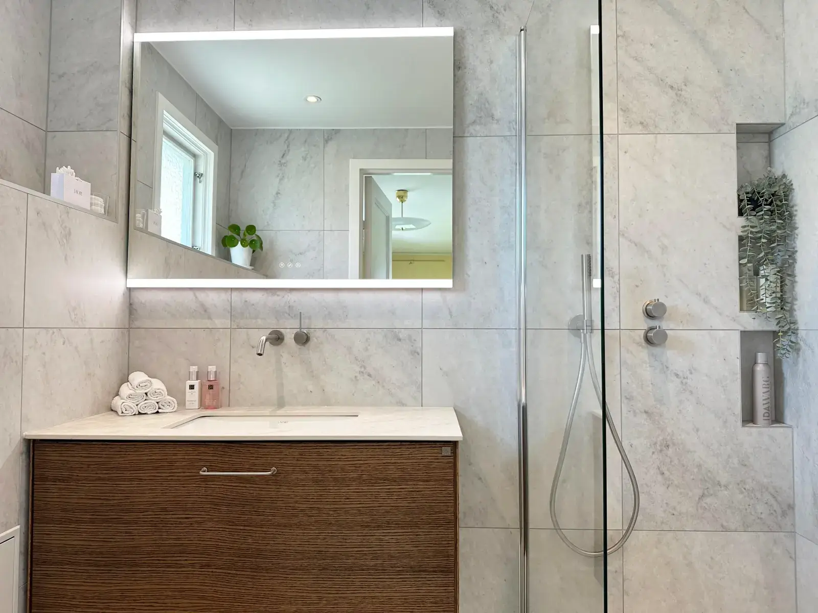 Modern kommod i trä med inbyggd belysningsspegel och eleganta detaljer i badrum Bromma.