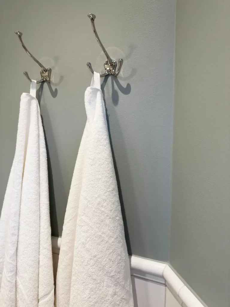 Detaljbild på vita handdukar upphängda på kromade krokar i badrumsrenovering i Nacka.