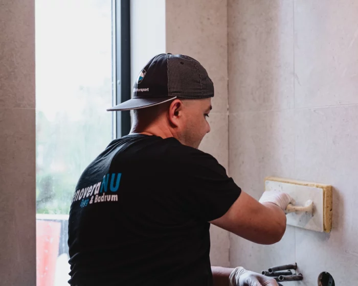 Renovera NU hantverkare som slätar ut fog på ljusa kakelplattor