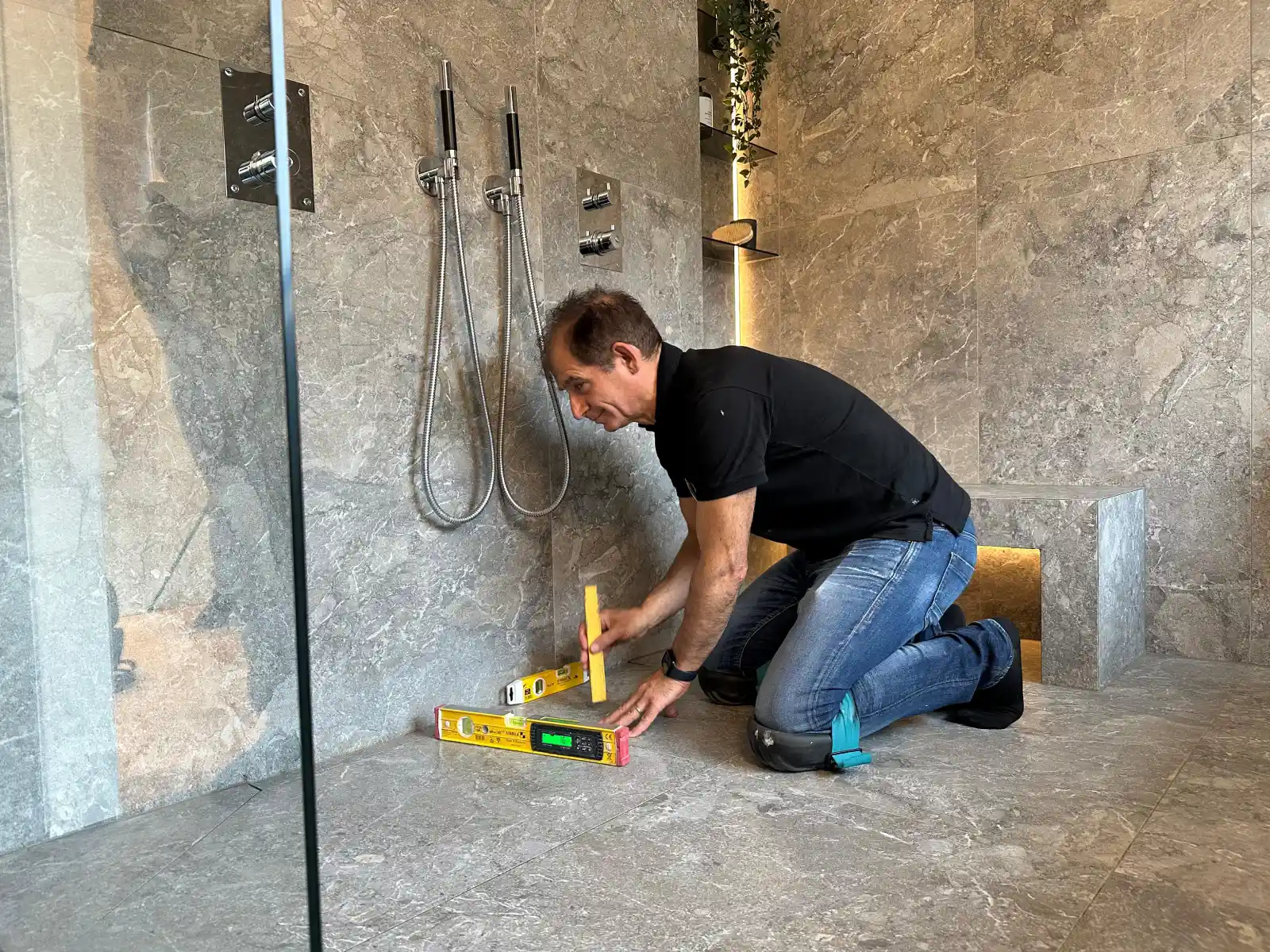 Hantverkare som arbetar för RenoveraNU gör besiktning i dusch vid badrumsrenovering i Stockholm med vattenpass