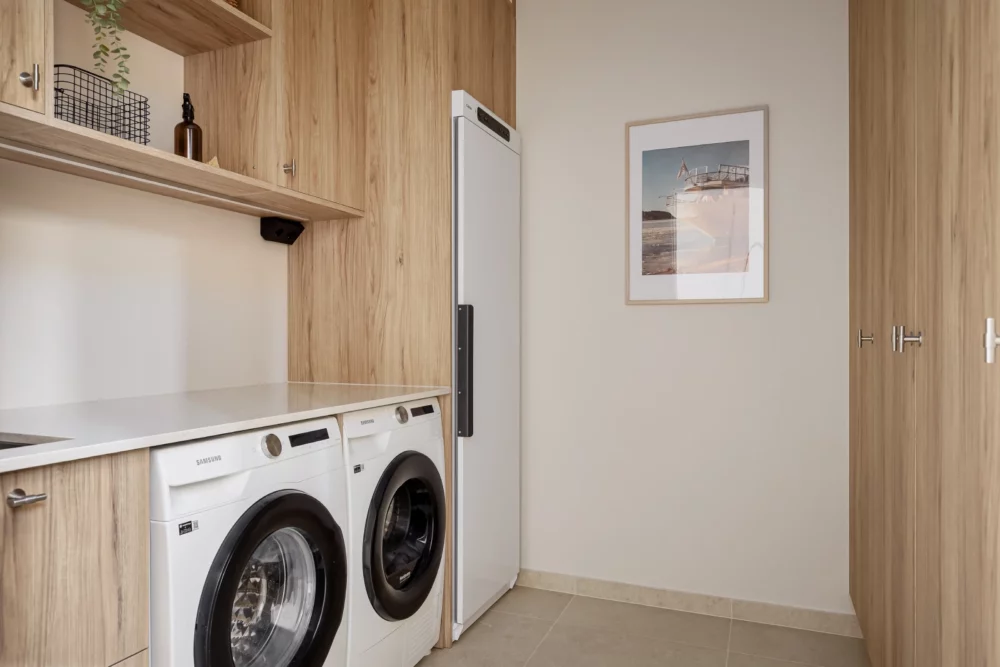 Modern tvättstuga med träinredning, tvättmaskin och torktumlare, tvättstugerenovering i Stockholm utförd av Renovera NU.